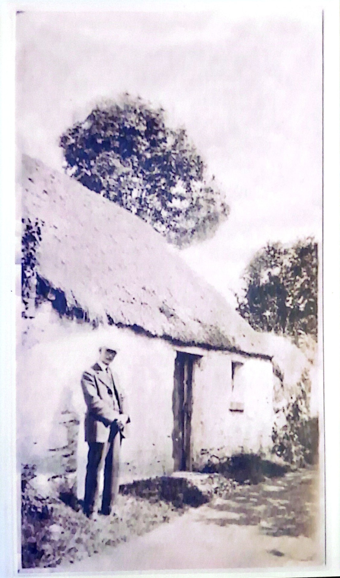 A man outside a thatched cottage, thought to be the cottage or blacksmith's house that became The Forge